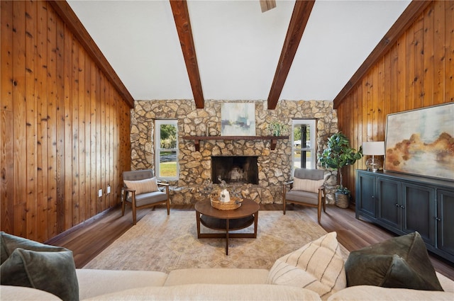 living room with a stone fireplace, light hardwood / wood-style flooring, beamed ceiling, high vaulted ceiling, and wood walls