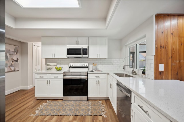 4500 Old Colony Rd, Mulberry, FL 33860 - kitchen with appliances with stainless steel finishes, wood finished floors, white cabinets, backsplash, and light stone counters