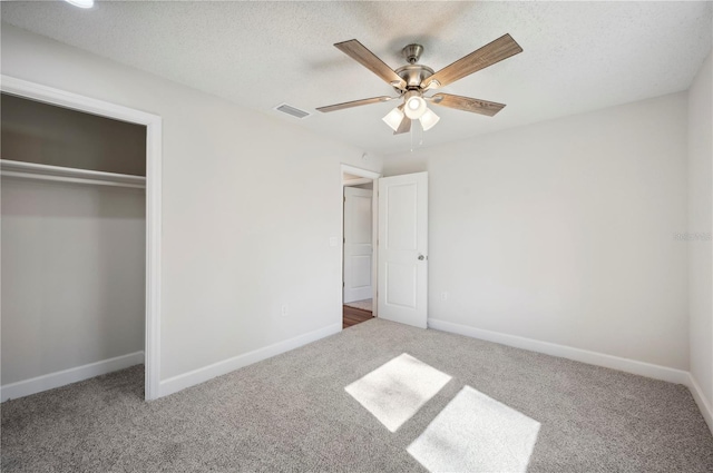 unfurnished bedroom featuring carpet flooring, ceiling fan, a textured ceiling, and a closet