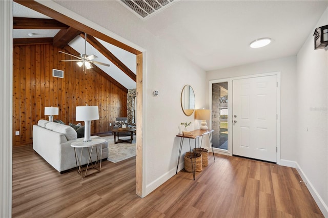 entrance foyer featuring vaulted ceiling with beams, ceiling fan, wood-type flooring, and wooden walls