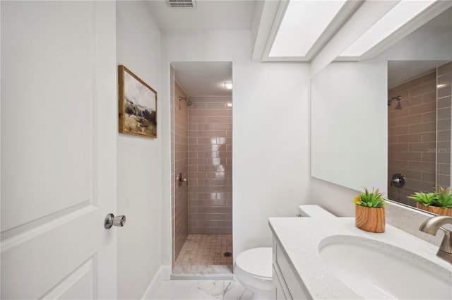 bathroom with vanity, toilet, and tiled shower