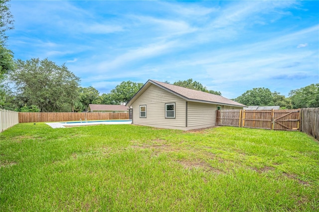 rear view of house featuring a lawn and an empty pool