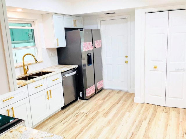 kitchen with sink, stainless steel appliances, light hardwood / wood-style floors, light stone countertops, and white cabinets