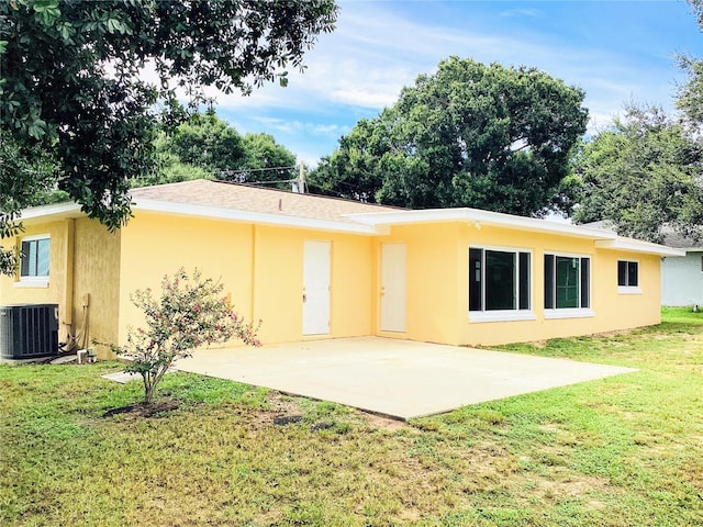 rear view of property featuring a patio, central AC, and a lawn