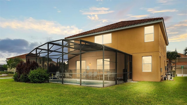 back of house featuring glass enclosure, a yard, an outdoor pool, and stucco siding