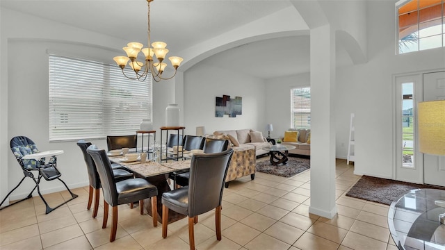 dining space featuring light tile patterned floors, baseboards, arched walkways, and a notable chandelier