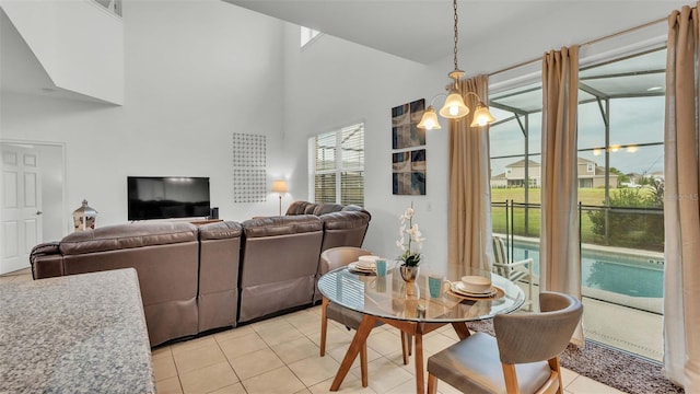 dining area with plenty of natural light, light tile patterned flooring, a chandelier, and a towering ceiling