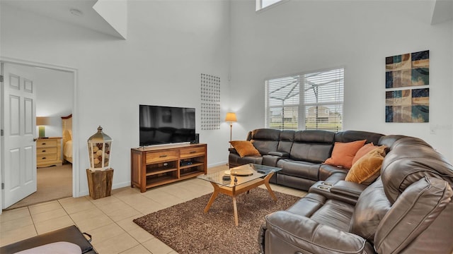 living area featuring a healthy amount of sunlight, light tile patterned flooring, baseboards, and a high ceiling