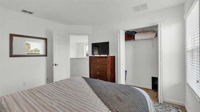 carpeted bedroom featuring multiple windows, a closet, and visible vents