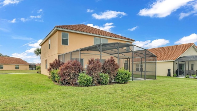 back of house with glass enclosure, a lawn, a tiled roof, and stucco siding