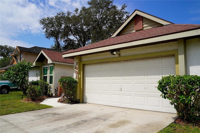 view of front of house featuring concrete driveway, roof with shingles, and stucco siding