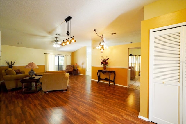 living room with a textured ceiling, ceiling fan with notable chandelier, and dark hardwood / wood-style flooring