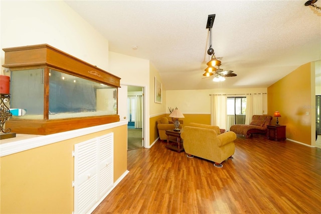 living room with vaulted ceiling, a textured ceiling, wood finished floors, and a ceiling fan