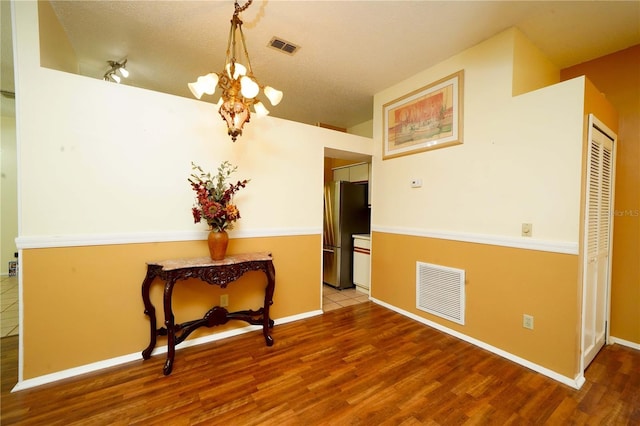 interior space featuring baseboards, visible vents, a chandelier, and wood finished floors