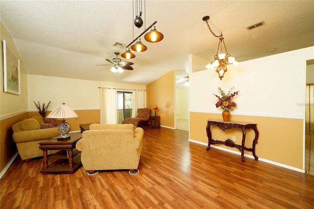 living room featuring rail lighting, a textured ceiling, ceiling fan with notable chandelier, and wood-type flooring