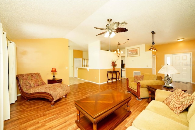 living room with light hardwood / wood-style floors, vaulted ceiling, and a textured ceiling