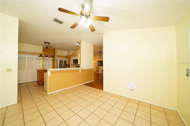 kitchen featuring a breakfast bar, stainless steel appliances, visible vents, light tile patterned flooring, and a peninsula