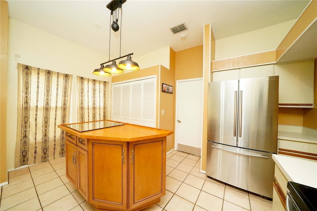 kitchen with decorative light fixtures, stainless steel fridge, range, and light tile patterned floors