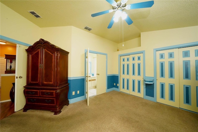 unfurnished bedroom featuring a textured ceiling, carpet flooring, two closets, and visible vents