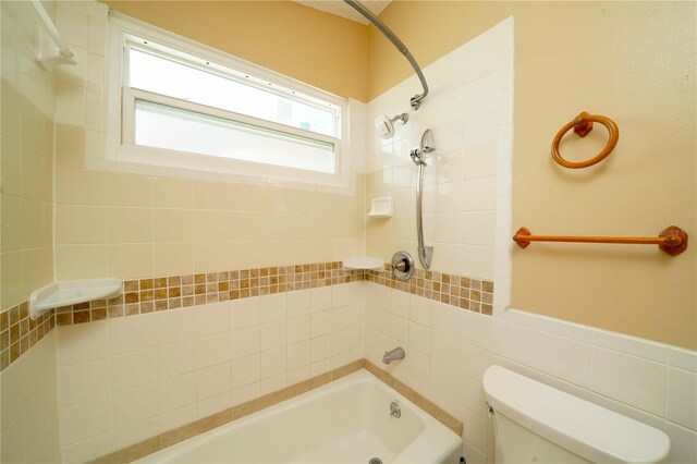 bathroom featuring tile walls, toilet, and tiled shower / bath