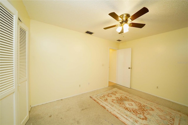 unfurnished bedroom with a textured ceiling, a closet, ceiling fan, and light carpet