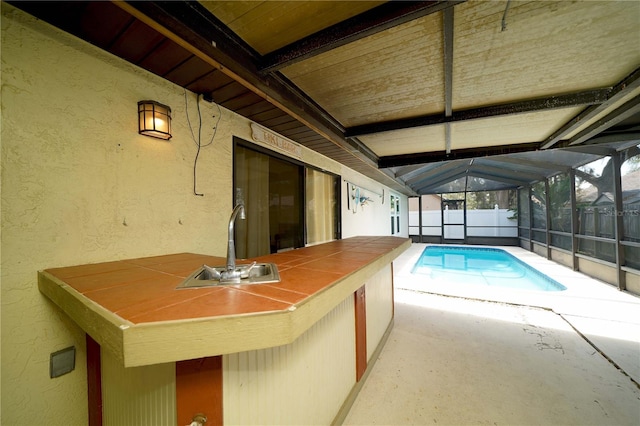 view of pool with sink, a lanai, and a patio area