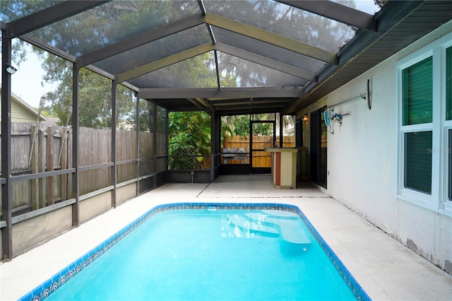 view of swimming pool featuring glass enclosure and a patio area