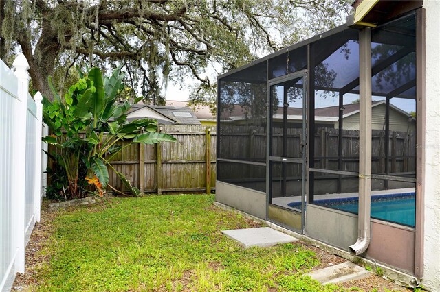 view of yard featuring glass enclosure, a fenced backyard, and a fenced in pool