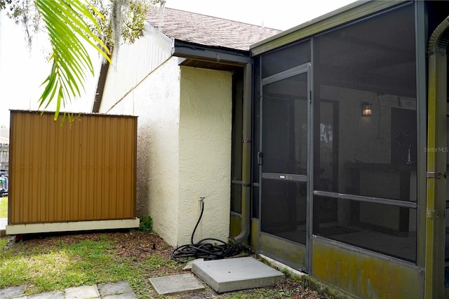 property entrance with a shingled roof and stucco siding