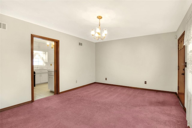 spare room featuring light colored carpet and an inviting chandelier