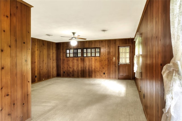 carpeted spare room with wood walls and ceiling fan