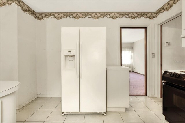 kitchen featuring light tile patterned flooring, electric range, and white fridge with ice dispenser