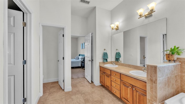 full bath with toilet, double vanity, tile patterned flooring, and ensuite bath