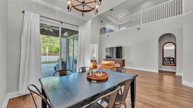 dining room with baseboards, a chandelier, wood finished floors, arched walkways, and crown molding