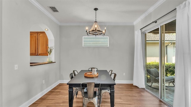 dining area with a chandelier, healthy amount of natural light, ornamental molding, and wood finished floors
