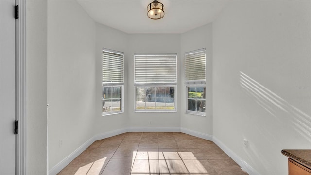 spare room with light tile patterned floors and baseboards