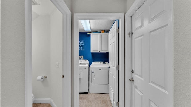 laundry room featuring separate washer and dryer, cabinet space, and a textured ceiling