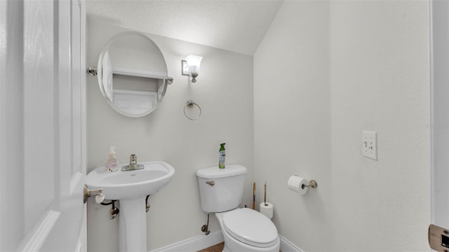 half bathroom with lofted ceiling, toilet, and baseboards