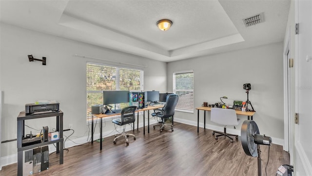 home office with a raised ceiling, wood finished floors, and baseboards