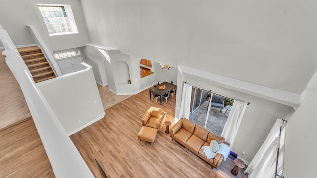 living room featuring a towering ceiling, wood finished floors, baseboards, and stairway