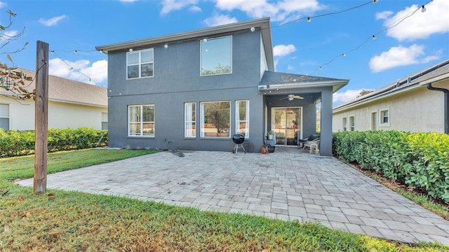 back of house featuring stucco siding, ceiling fan, a yard, and a patio