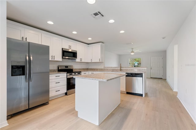 kitchen featuring white cabinetry, light hardwood / wood-style flooring, a kitchen island, kitchen peninsula, and stainless steel appliances