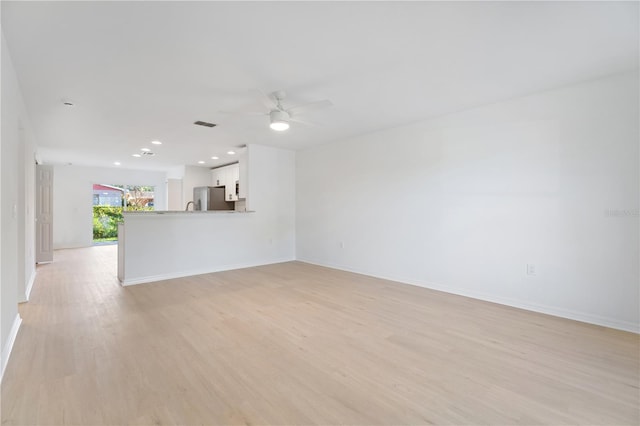 unfurnished living room featuring ceiling fan and light hardwood / wood-style floors