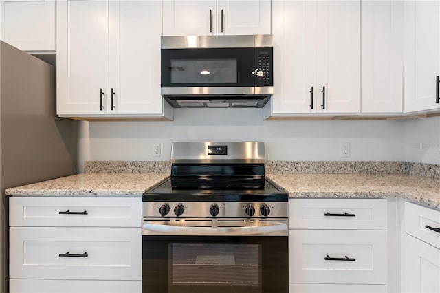 kitchen with white cabinets, light stone counters, and stainless steel appliances