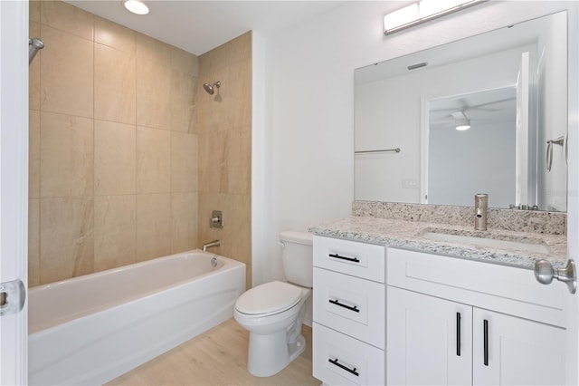 full bathroom featuring tiled shower / bath combo, toilet, wood-type flooring, and vanity