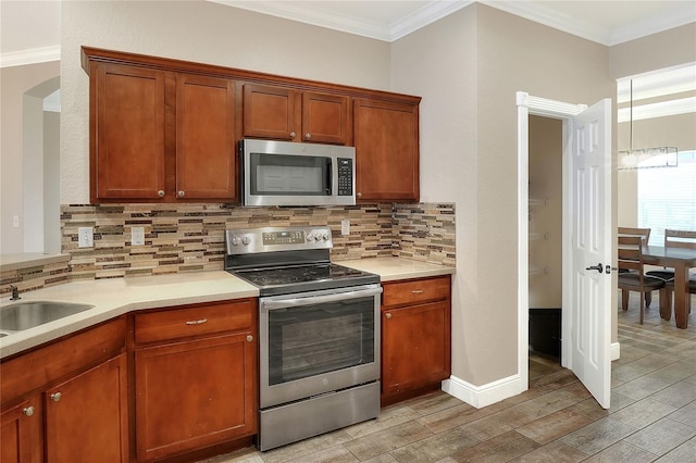 kitchen with sink, stainless steel appliances, light hardwood / wood-style flooring, backsplash, and crown molding