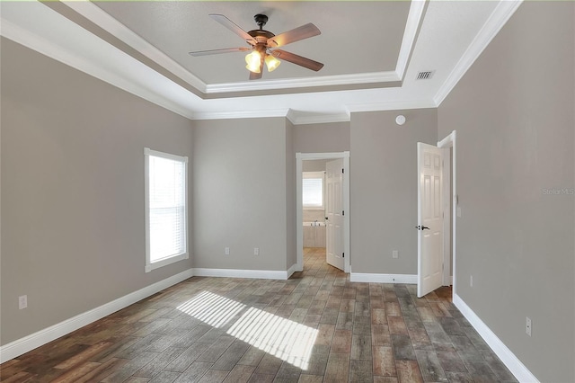 unfurnished bedroom featuring dark hardwood / wood-style floors, ceiling fan, ornamental molding, and a tray ceiling