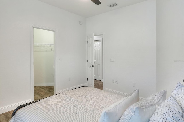 bedroom featuring light wood-type flooring, a walk in closet, a closet, and ceiling fan