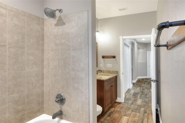 full bathroom with tiled shower / bath, toilet, vanity, and hardwood / wood-style flooring