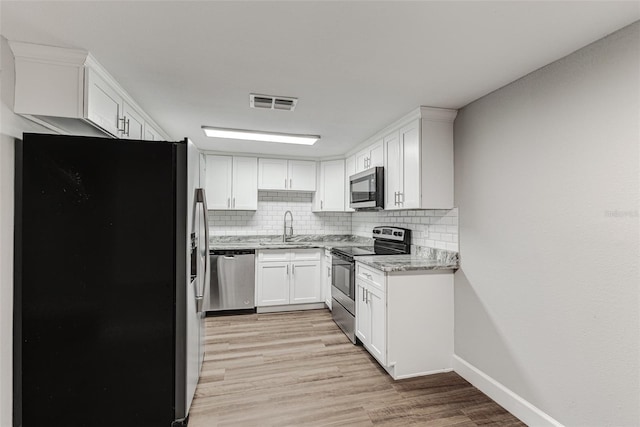 kitchen featuring tasteful backsplash, visible vents, white cabinets, stainless steel appliances, and a sink